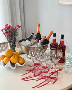 there are many glasses on the table with bottles and oranges next to each other