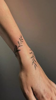 a woman's hand with a small tattoo on the wrist and an olive branch