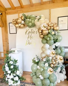 the balloon arch is decorated with flowers and greenery