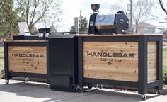 an outdoor coffee shop with two large wooden boxes on the side and one small bar behind it