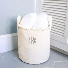 a white laundry basket with two personalized towels in it on the floor next to a door