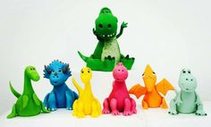 a group of toy dinosaurs sitting next to each other on a white surface with one dinosaur standing in the middle