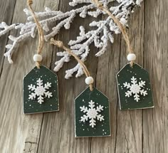 three snowflakes are hanging from the top of a wooden table next to some branches