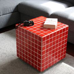 a red and white box sitting on the floor next to a couch