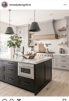 a large kitchen with an island in the middle and two hanging lights over it's sink