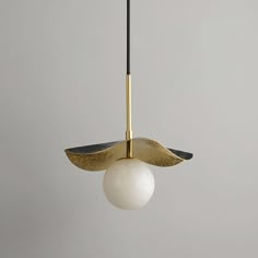 a white ball hanging from a brass colored light fixture with black and gold details on it