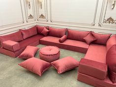 a large red couch sitting in the middle of a living room with pillows on it