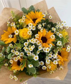 a bouquet of sunflowers and daisies in brown paper