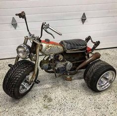 an old motorcycle is parked in front of a garage door with no one around it