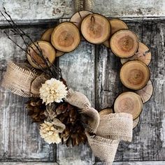 a wreath made out of wood slices and burlocks with flowers on it is hung on a door