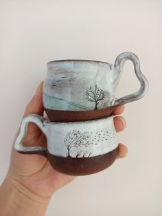 two handmade mugs with trees painted on them