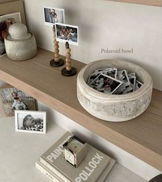 a wooden shelf topped with pictures and other items on top of a table next to a book