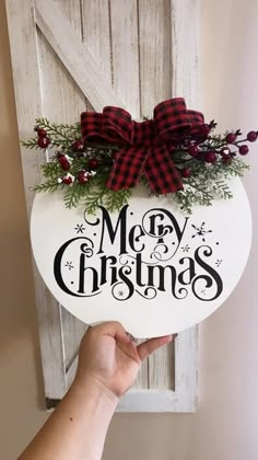 a hand holding up a merry christmas sign with red and black bows on it's head