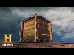 a large building sitting on top of a desert covered ground next to a sky filled with clouds