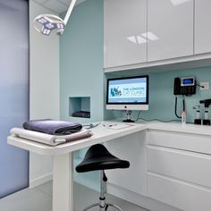 a desk with a computer monitor, keyboard and mouse on it in a white room