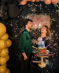 a man and woman standing in front of a cake