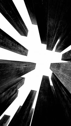 black and white photograph of tall buildings looking up at the sky with sunbeams