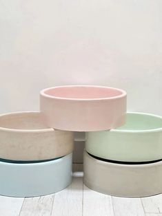 three bowls sitting on top of each other in front of a white wall and floor