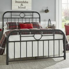 a bedroom with a metal bed frame and plaid pillows on the pillowcases in front of the bed