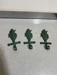 three green cast iron door handles with flowers on each one and two hooks in the middle