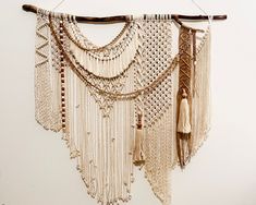 a wall hanging with beads and tassels attached to it's sides on a white wall