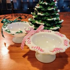 two white dishes with candy canes in front of a christmas tree on a table