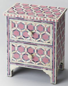 a pink and white cabinet with geometric designs on the front, two drawers at the bottom