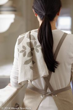 a woman with long hair wearing a white shirt and brown suspenders is looking out the window