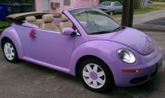 a purple convertible car parked in front of a pink house