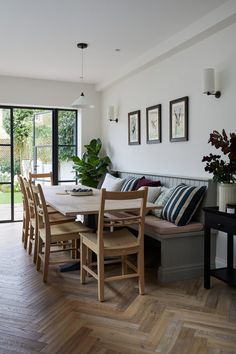 a dining room table and chairs with wooden flooring in front of large glass doors