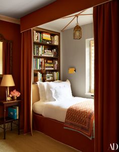 a bedroom with red curtains and a bed in the corner next to a bookshelf