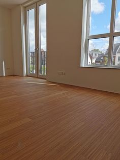 an empty room with wooden floors and large windows