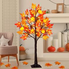 a lighted tree in the middle of a living room with fall leaves on the floor