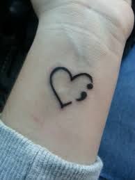 a small tattoo on the wrist of a woman with a heart and stethoscope