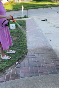 a woman in a purple dress is using a lawn trimmer