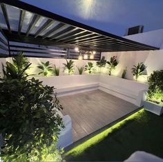 an outdoor living area is lit up with lights and potted plants on the deck