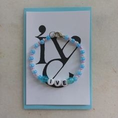 a beaded bracelet with the word love is displayed on top of a greeting card