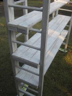 a white wooden shelf sitting on top of a grass covered field