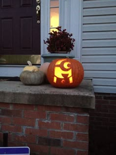 a pumpkin carved to look like an elephant sitting on top of a brick wall in front of a house