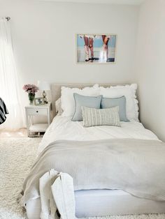 a bedroom with a white bed and two pictures on the wall