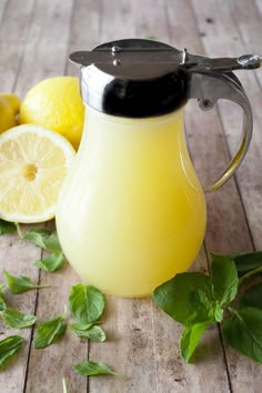 a lemon cream syrup in a glass pitcher next to sliced lemons