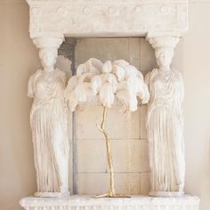 a white marble fireplace mantel with statues on it