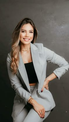 a woman in grey suit posing for the camera with her hands on her hips and one hand on her hip