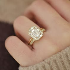 a close up of a person's hand wearing a ring with an emerald stone