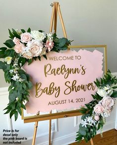 a welcome sign for a baby shower with flowers and greenery around it on an easel