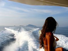 a woman sitting on the back of a boat in the ocean