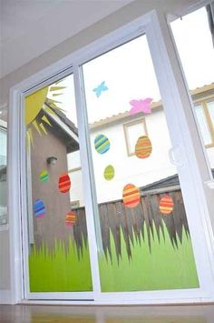 an open window with paper cut outs on the outside and grass in front of it