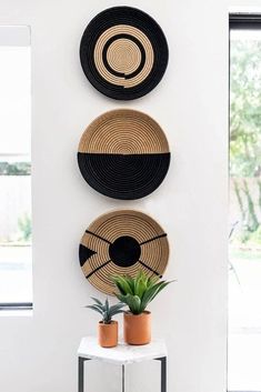 three black and white plates hanging on the wall next to a potted succulent