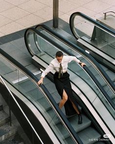 a man riding an escalator down a set of stairs with his arms outstretched