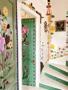 a green door with flowers painted on it and some stairs leading up to the second floor